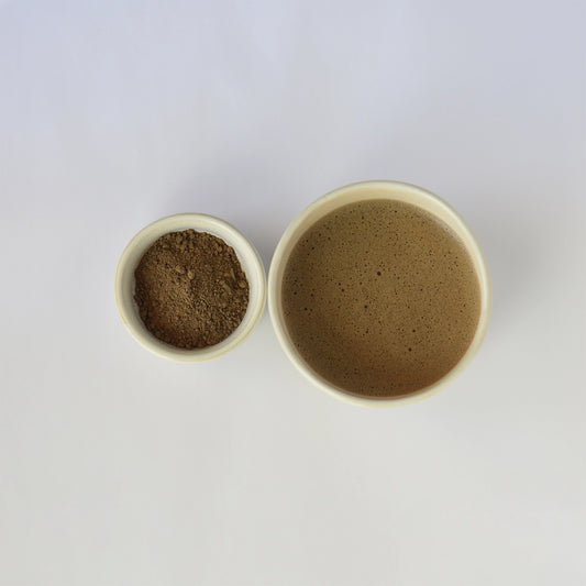 Two small ceramic bowls, one filled with a light roast hojicha powder and the other light roast hojicha on a white background