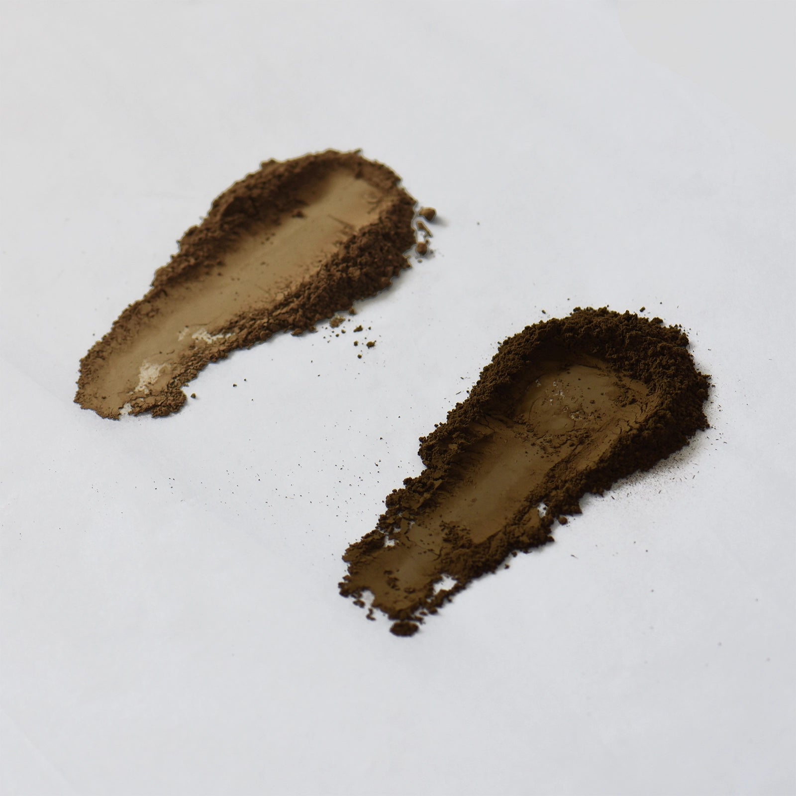 Two swatches of hojicha powder on a white background