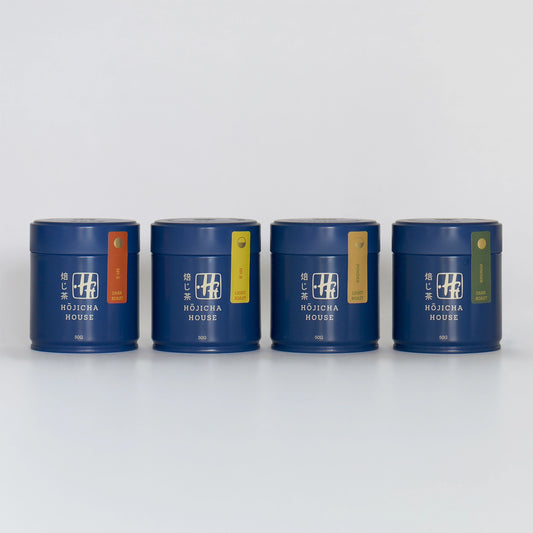Four blue hojicha tea canisters with colorful labels on a white background