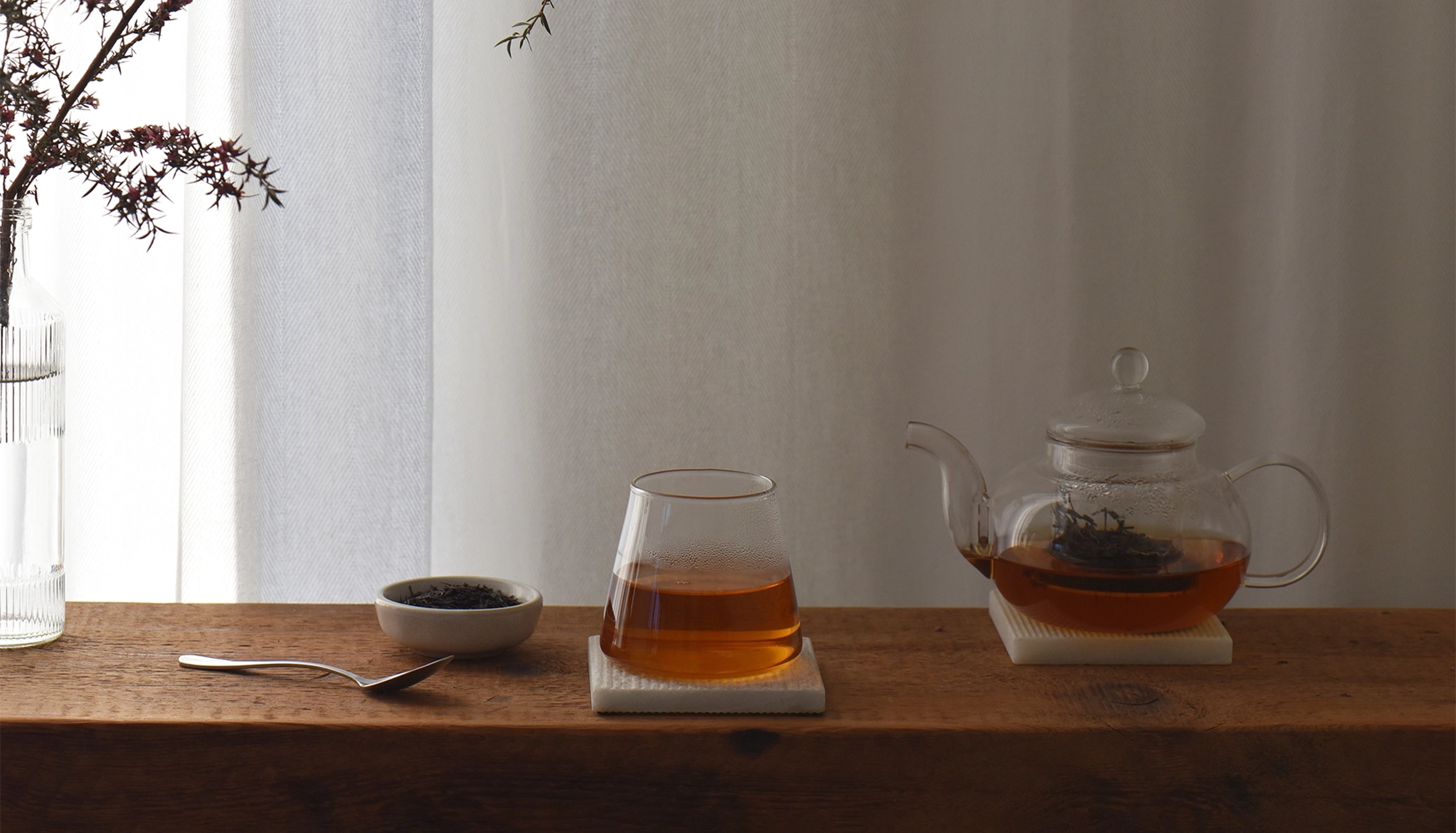 Tea set with glass teapot and cup on a wooden surface with a neutral background