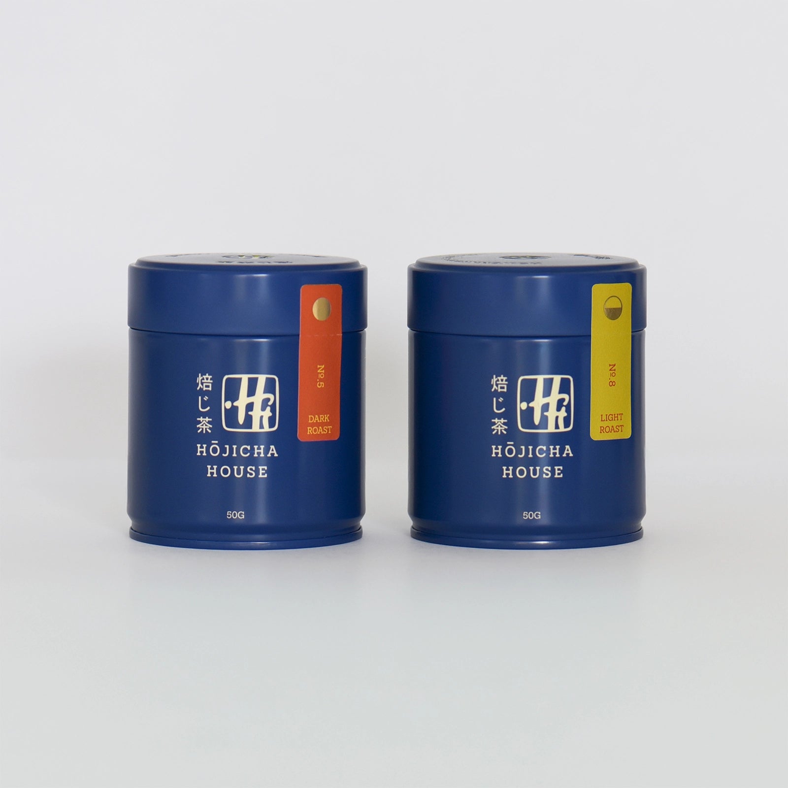 Two blue tea canisters with labels from Hojicha House on a white background