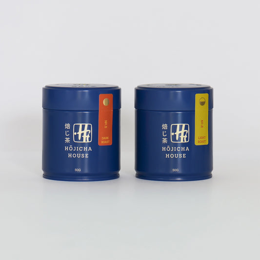 Two blue tea canisters with labels from Hojicha House on a white background